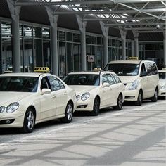 several cars are lined up in front of an airport terminal with taxi cabs parked on the side