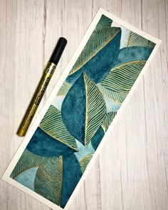 a pen sitting on top of a piece of paper next to a drawing pad with leaves