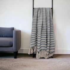 a blue chair sitting in front of a white wall next to a gray and black blanket