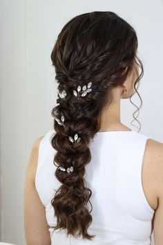 a woman with long dark hair wearing a white dress and some flowers in her hair