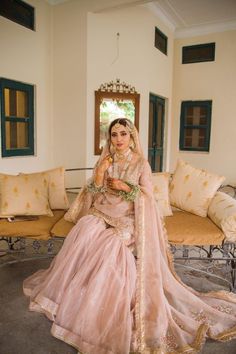 a woman in a pink lehenga sitting on a couch