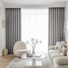 a living room with white furniture and curtains