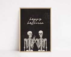 two skeletons holding scissors in front of a black background with the words happy halloween written on it