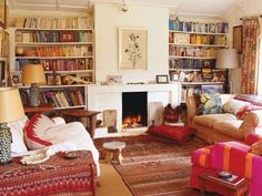 a living room filled with lots of furniture and bookshelves next to a fire place