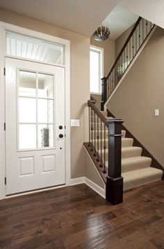 a staircase leading up to a white door in a home with hardwood floors and hard wood flooring