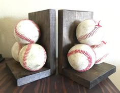 three baseballs are stacked on top of each other in wooden blocks with red stitching