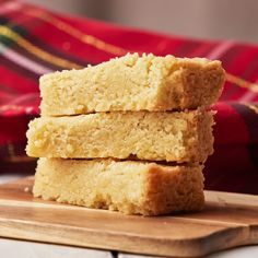 three pieces of cake sitting on top of a wooden cutting board next to a plaid cloth