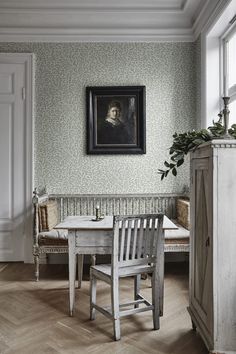 a room with a table, chair and painting on the wall