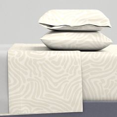 three pillows stacked on top of each other next to a bed sheet and pillow case