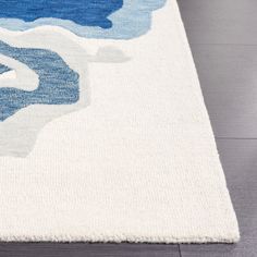 a blue and white area rug with waves on the top, in front of a wooden floor