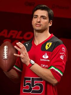 a man holding a football in his right hand while wearing a red shirt and black pants