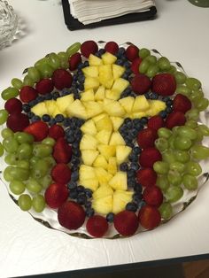 a cake made to look like a cross with fruit on top and grapes in the middle