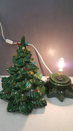 a small green christmas tree lamp sitting on top of a table next to a light bulb