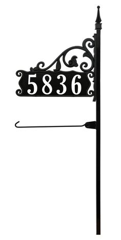 a black and white photo of a street sign with numbers on the front, and an ornamental design at the top