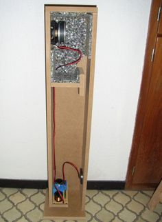 an electrical device is in a cardboard box on the floor next to a white wall