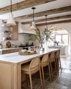 a kitchen with wooden beams and white counter tops next to a dining room table filled with chairs