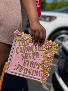 a close up of a person holding a pink and gold sign with words on it