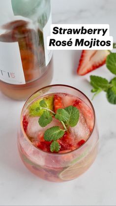 a close up of a drink in a glass with strawberries and mint on the side