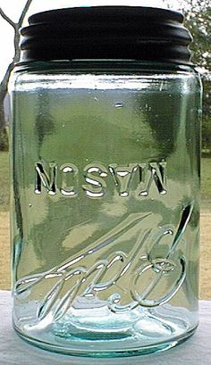 a glass mason jar sitting on top of a table next to a tree and grass