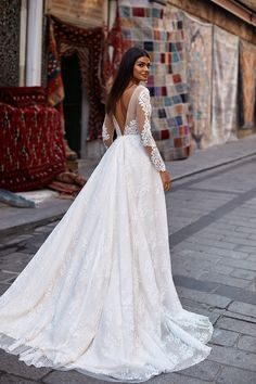 a woman in a wedding dress is standing on the street with her back to the camera