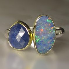 Gorgeous Australian Boulder Opal Doublet(6.3 X 11.8mm, 1.13cts) paired with a beautiful, natural, untreated, rose cut blue sapphire(1.97cts, 7.2 X 8.8mm). Each stone is set in a solid 18k gold bezel with fine silver backsheets under the stones. Sterling silver band- approx. 2.9mm wide. All metal is from recycled sources. This ring is a size 7 1/2 and I can stretch to a 7 3/4. Photos have been taken up close for detail. Please refer to dimensions. Attractively boxed. INTERNATIONAL BUYERS: Insured first class.  Buyer is responsible for any customs taxes/fees. Multistone Ring, Boulder Opal Ring, Ethiopian Opal Ring, Ring Opal, Blue Sapphire Ring, Australian Boulder Opal, Blue Sapphire Rings, 4 Photos, Opal Ring