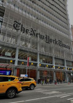 the new york times building is shown in this cityscape photo, with taxis passing by