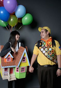 a man and woman dressed in costumes standing next to each other with balloons behind them