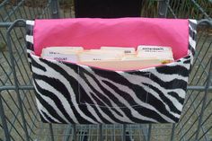 a shopping cart with a zebra print bag in the front and two file folders in the back