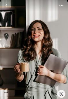 a woman holding a laptop and coffee in her hand