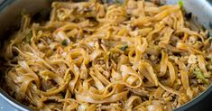 a pan filled with noodles and vegetables on top of a wooden table