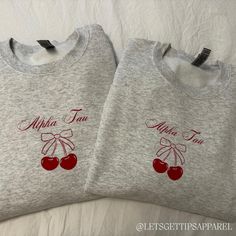 two sweatshirts with cherries on them that say, albia fan and an apple