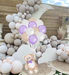 there is a teddy bear holding balloons in the air