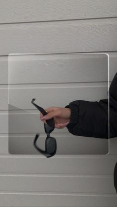 a woman holding a cell phone in her right hand while standing next to a garage door