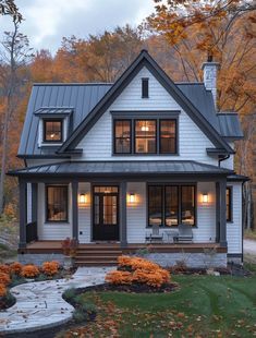 a white house in the fall with lots of leaves on the ground and trees around it