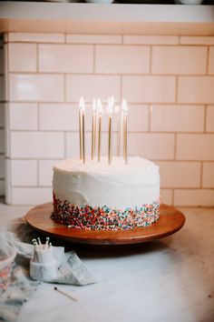 a white cake with sprinkles and lit candles