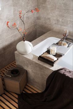 a bathroom with a bathtub, trays and towels on the floor next to it