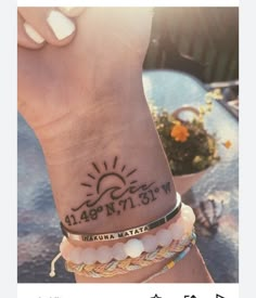 a woman's wrist with a sun tattoo on her left arm and two bracelets attached to the wrist