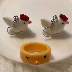 two white birds with red heads are sitting on a plate next to a yellow ring