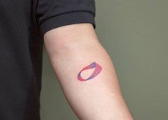 a person's arm with a red and blue circle tattoo on the left forearm