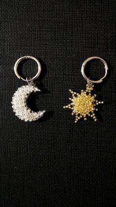 two keychains that have some kind of star and moon in them on a black surface