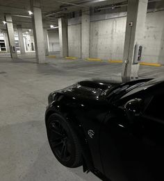 a black sports car is parked in an empty parking garage with no one around it