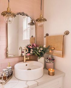 a white sink sitting under a bathroom mirror next to a pink tiled wall with flowers on it