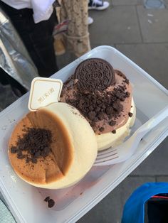 a plastic container filled with desserts on top of a table next to a sidewalk