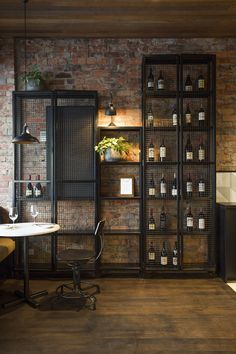 an office with brick walls and shelves filled with bottles, wine glasses and other items