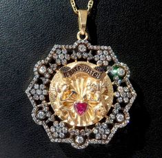 Vintage french ' il bat pour toi ' the 70's charm pendant set 1 heart cut natural ruby 0.30 ct ( dim 4 x 4 x 3 mm ) & 136 modern cut diamonds 0.01 ct & 48 modern cut diamonds 0.02 ct & 42 modern cut diamonds 0.03 ct & 12 modern cut diamonds 0.03 ct & 6 modern cut diamonds 0.1 ct for a total of diamonds 0.98 ct, solid yellow gold 18k, weight 13.90 gr, center diameter 36 mm ( 1 1/2 inch ), movable cherubs, hallmarked : 1 eagle head french punch 750 ( gold 18k ), natural orange Hallmarked Medallion Jewelry For Valentine's Day, Collectible Medallion Jewelry For Valentine's Day, Vintage Diamond Jewelry For Valentine's Day, Collectible Pendant Jewelry For Valentine's Day, Love Pendant, Eagle Head, Love Charms, Watch Chain, Diamond Fashion