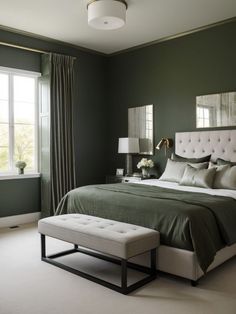 a bedroom with green walls, white bedding and a bench in front of the window