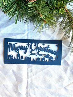 a christmas ornament hanging from a pine tree with the words merry christmas on it