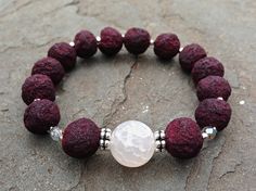 a beaded bracelet with red lava beads and a white glass bead on it