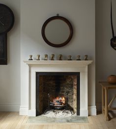 a living room with a fire place and clock on the wall