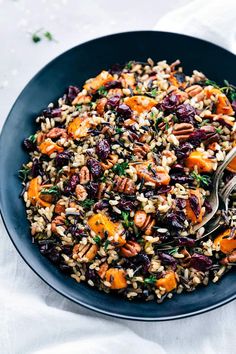 a bowl filled with rice and vegetables on top of a white cloth next to a spoon